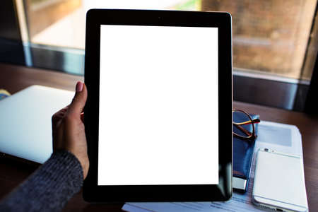Close up business woman holding touch pad with blank mock up copy space screen background for promotional content against workstation with closed laptop computer and working tools. Digital tabletの写真素材