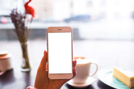 Closely hipster girl holding modern white mobile phone with blank display with copy space background...
