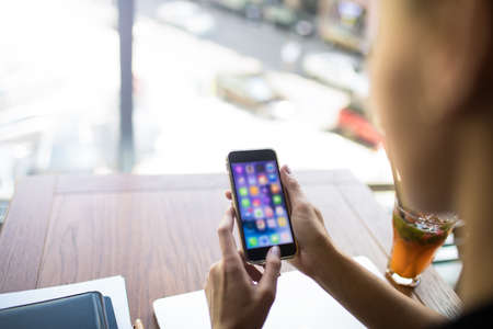 Business woman using applications on modern mobile phone while sitting in restaurant during work break near copy space for promotional content. Female online booking via cell telephone gadgetの写真素材