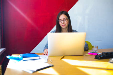 Hipster girl in glasses and casual wear skilled freelance social media content writer reading news...