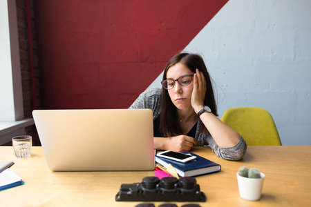 Female worker feeling lack of motivation, tired and sad, thinking about problem while sitting at...