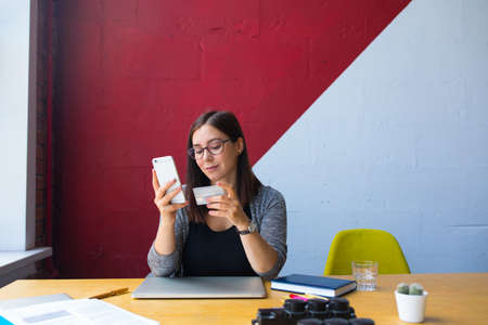Female prosperous entrepreneur online ordering via smartphone and using credit debit card for...
