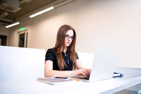 Woman professional writer keyboarding on laptop computer, sitting in coworking space. Female...