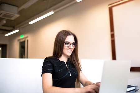 Smiling business woman having video conference via laptop computer, sitting in office. Happy female...