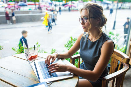 Female successful pr manager using applications on laptop computer while sitting in coffee shop. Business woman checking e-mail on notebook during break in restaurantの写真素材