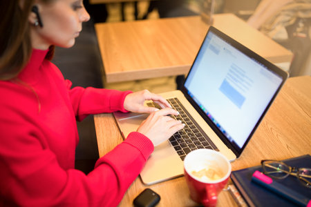 Clever female publication specialist remote work on laptop computer while sitting in restaurant during work break.の写真素材