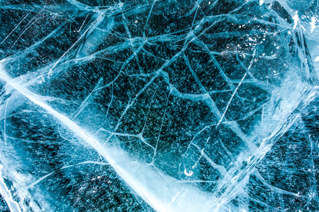 Top views of a texture cracks transparent ice on a Baikal lake on a snowy winter day
