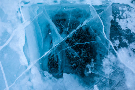View from above on a natural blue cracked ice texture of surface of frozen Baikal Lake in cold snow winter day. Backdrop with copy space for advertisingの写真素材