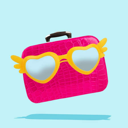 Pink happy suitcase with with flying sunglasses yellow wings summer travel holiday vacationの写真素材