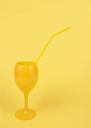 Yellow cocktail glass summer drink beverage juice with yellow straw party concept minimal aestheticの写真素材