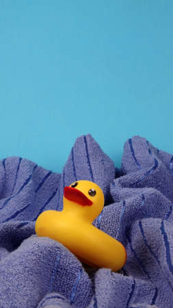 Yellow rubber duck toy on blue towel waves abstract concept photo of turbulent sea or ocean on blue copy space backgroundの写真素材