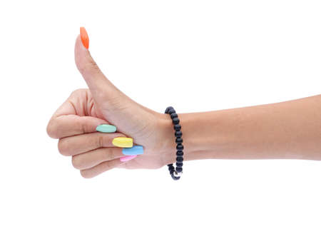 Beautiful colorful nails on female hand gesturing thumb up isolated on white background. Modern fancy manicure beauty conceptの写真素材