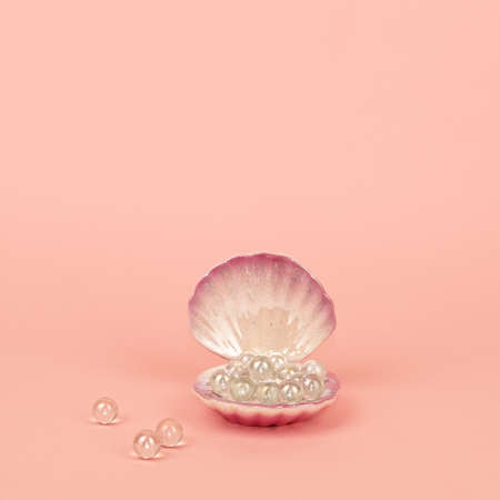 Beautiful seashell full of shiny pearls on pink background. Concept of value of sea shell pearl and fortune. Symbol of wealthy lifeの写真素材