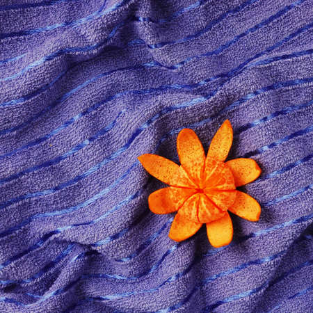 Abstract orange mandarin peeled on sea like blue towel as summer symbol. Holiday vacation concept. Fruit as Sun and textile surface as sea or ocean water conceptの写真素材