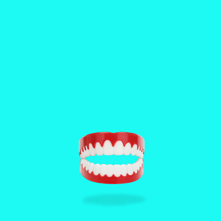 Abstract artificial teeth jaws item isolated on turquoise blue background. Funny mouth concept ideaの写真素材