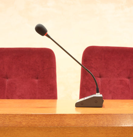 Black microphone against empty seats in lecture room concept photo. Lecturer speaker show sceneの写真素材