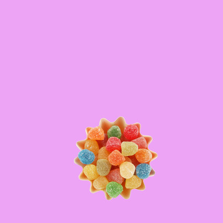 Jelly sweets colorful candies gumdrops in muffin baking paper cup box on square pink background. Sweet confectionery candy gumdrops view from above concept idea photoの写真素材