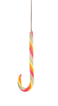 Lolly candy cane shaped as fishing hook sugar bait isolated on white background. Ambiguous catching concept. Prepared decoy for being hooked on sweetsの写真素材