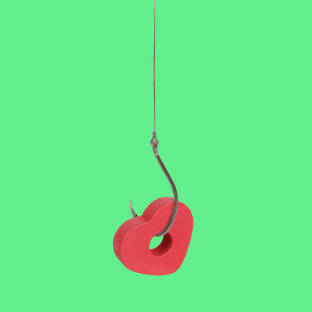 Pierced heart wooden symbol of love isolated on green background. Loving concept