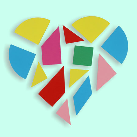 Colorful wooden heart love teaser puzzle isolated on bright green square background. Loving romance...