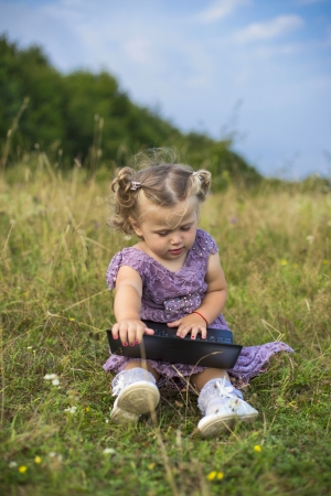 little girl with a computer on the natureの写真素材