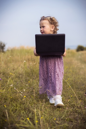 Little girl with laptop on the natureの写真素材