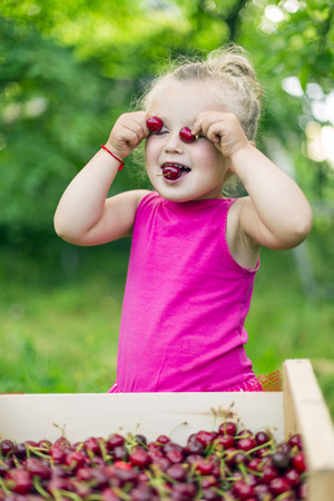 little girl with a sweet cherry on natureの写真素材