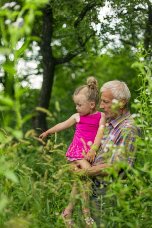 Grandfather with granddaughter outdoors in summerの写真素材