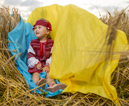 girl in Ukrainian national costume in a wheat fieldの写真素材