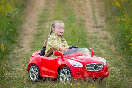 little girl riding a red carの写真素材