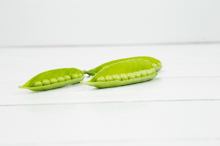 raw peas on a white wooden table