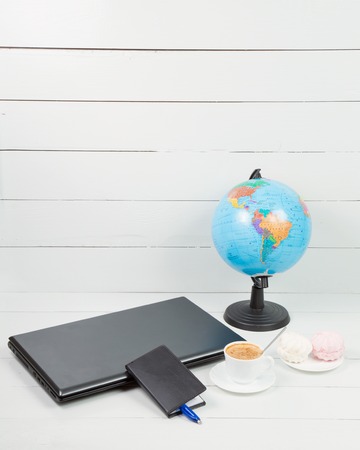 Globe Coffee and notebook on a wooden tableの写真素材