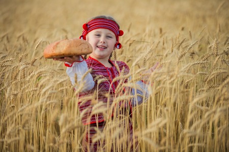 Child in Ukrainian national costume with a loaf of bread in her handの写真素材
