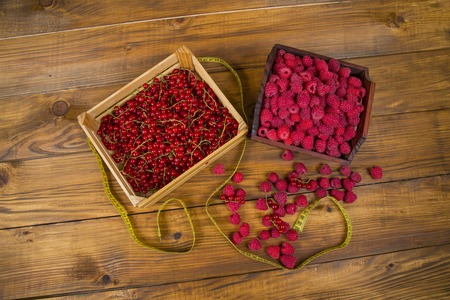 currants, raspberries and tape measure on wooden tableの写真素材