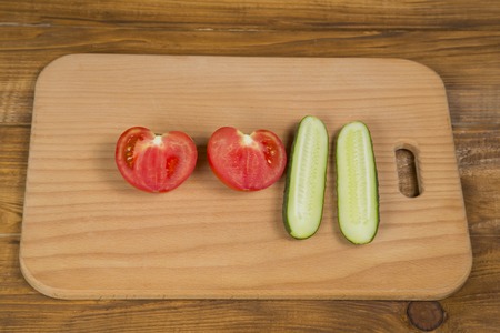sliced tomato and cucumber on a wooden trayの写真素材