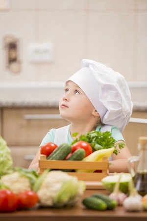child cook with vegetables in the kitchenの写真素材