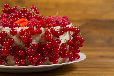Cake with strawberries and raspberries currants on a wooden table