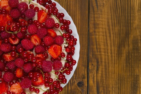 Cake with strawberries and raspberries currants on a wooden tableの写真素材