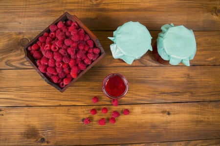 raspberries and raspberry jam on a wooden table