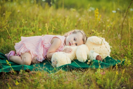 little girl with a teddy bear on natureの写真素材