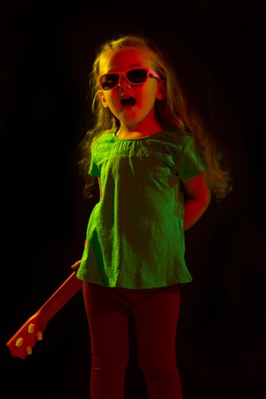 child with a guitar on a black backgroundの写真素材