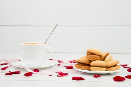 cup of coffee and a rose on a white wooden tableの写真素材