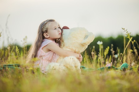 little girl with a teddy bear on natureの写真素材