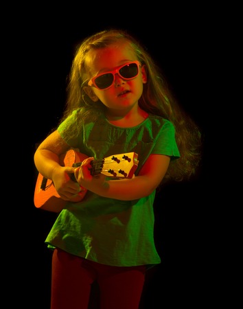 child with a guitar on a black backgroundの写真素材