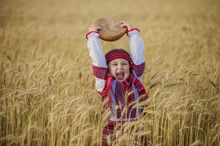 Child in Ukrainian national costume with a loaf of bread in his handの写真素材