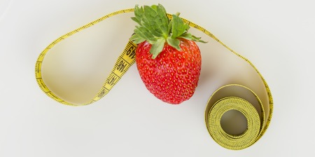 Strawberries with measuring tape on a white backgroundの写真素材