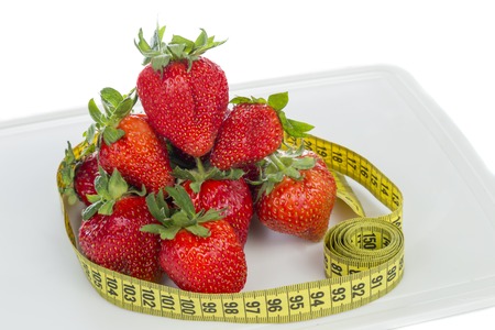 Strawberries with measuring tape on a white backgroundの写真素材