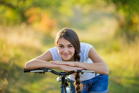 Girl with a bicycle in a summer parkの写真素材