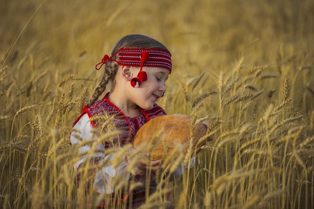 Child in Ukrainian national costume with a loaf of bread in his handの写真素材