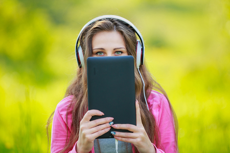 Girl hiding behind the headphones tabletの写真素材